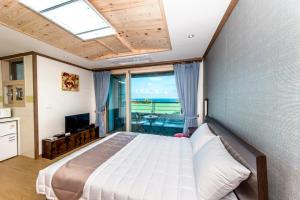 1 dormitorio con 1 cama y vistas al océano en Sea and Wave en Seogwipo