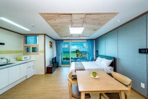 1 dormitorio con cama, mesa y cocina en Sea and Wave en Seogwipo