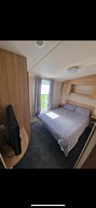 a bedroom with a bed and a flat screen tv at 136 Beech at Flamingo Land in Malton
