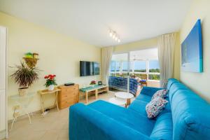 niebieską kanapę w salonie z dużym oknem w obiekcie Top Strandwohnung Marina Park w Cala Millor