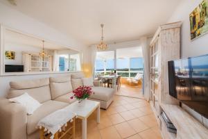 ein Wohnzimmer mit einem Sofa und einem TV in der Unterkunft Strandwohnung Marina Park Playa in Cala Millor