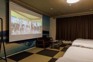 大阪市にあるカーサコモダ難波のベッド2台が備わる客室で、プロジェクションスクリーンが付いています。