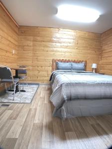 1 dormitorio con 1 cama y pared de madera en Soldotna Lodge en Soldotna