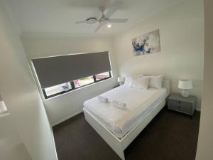a bedroom with a white bed and a window at Stunning 2story villa Near Canal in Gold Coast