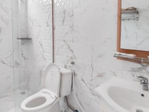 a white bathroom with a toilet and a sink at Pandawa Villa Pangandaran in Pangandaran +1 photo