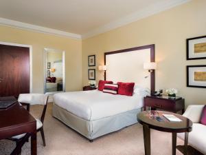 a hotel room with a bed and a table and a desk at Mövenpick Grand Al Bustan in Dubai