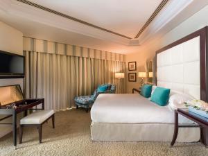 a hotel room with a large bed and a desk at Mövenpick Grand Al Bustan in Dubai