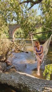 uma mulher está sentada numa rede num rio em Rêve Aveyron em Broquiès