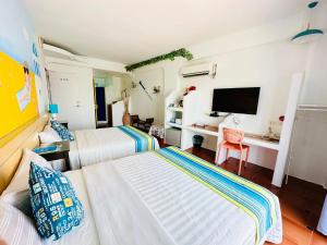 1 dormitorio con 2 camas y escritorio con TV en 海灘戀情 Beach Love 近沙灘-國旅卡特約商店, en Eluan