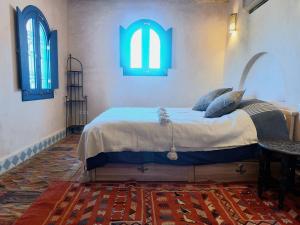 um quarto com uma cama grande e 2 janelas em Bab El Atlas em El Kelaa des Mgouna