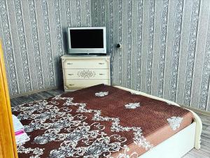 a bedroom with a tv and a dresser with a bed at Однокомнатная квартира Авангард 2 in Atyrau