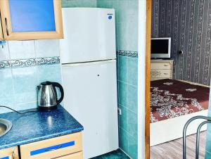 a kitchen with a white refrigerator and a sink at Однокомнатная квартира Авангард 2 in Atyrau