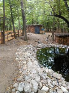 a pond in a park with trees and a fence at Roulotte avec piscine la jonquille in Valgorge