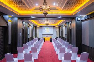 a row of white chairs in a room with a stage at Amman Unique Hotel in Udon Thani