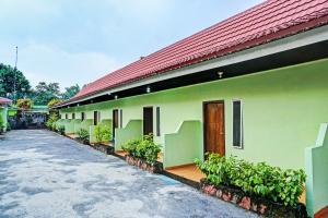 a green building with a red roof at OYO 92405 Evergreen Hotel & Resto 