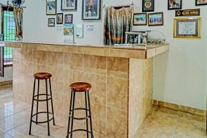 a bar with two stools in a room at OYO 92405 Evergreen Hotel & Resto 