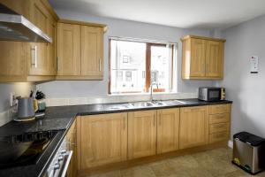 a kitchen with wooden cabinets and a sink and a window at Mourne Air & BBQ Shack in Newcastle