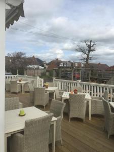 a patio with tables and chairs on a deck at Dunstan House in Burnham on Sea