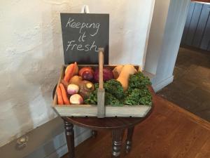 a basket of vegetables on a table with a sign at Dunstan House in Burnham on Sea