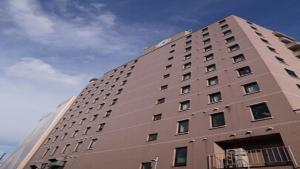 ein großes braunes Gebäude mit einem Himmel im Hintergrund in der Unterkunft HOTEL BRIGHT INN MORIOKA in Morioka