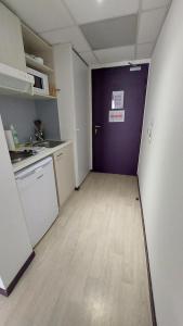 an empty room with a purple door and a kitchen at Studio moderne et équipé Lourdes Centre in Lourdes