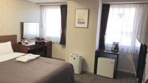 a hotel room with a bed and a desk and window at HOTEL BRIGHT INN MORIOKA in Morioka