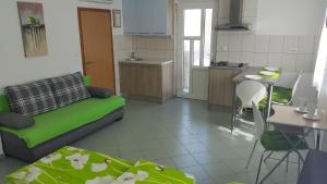 sala de estar con sofá verde y cocina en Apartments Carmen, en Jurdani