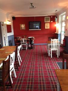 a restaurant with red walls and wooden tables and chairs at Dunstan House in Burnham on Sea