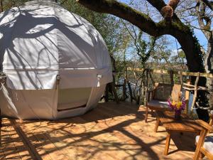 une tente en forme de dôme assise sur une terrasse à côté d'une chaise dans l'établissement Les Robinsonades, à Couladère