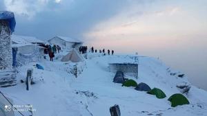 a group of people standing around tents in the snow at Triund Trek and Camping in Dharamshala