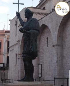 eine Statue eines Mannes, der ein Kreuz vor einem Gebäude hält in der Unterkunft B&B Dama3 in Barletta