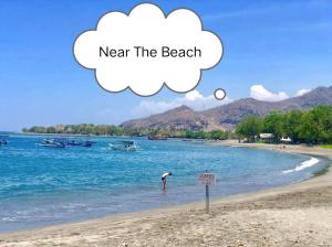 a person standing on a beach with a thought bubble near the water at Putu Guest House Pemuteran in Pemuteran