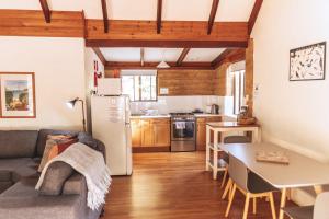 Bussells Bushland Cottages في مارغريت ريفر: مطبخ وغرفة معيشة مع أريكة وطاولة