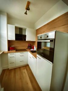 a kitchen with white cabinets and a stainless steel refrigerator at Flat Hundertwasser in Erfurt