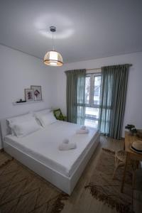 a bedroom with a large white bed and a window at Evergreen Apartment San Pietro in Durrës
