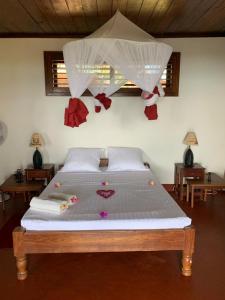 a bedroom with a large bed with white sheets and decorations at WINGS HOTELS in Nosy Be