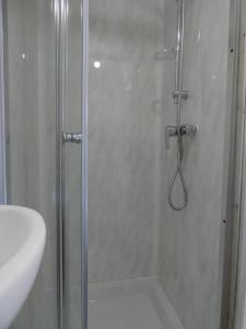 a shower with a glass door next to a sink at Bridge Street En Suite Rooms in Merthyr Tydfil