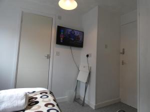 a bedroom with a bed and a television on the wall at Bridge Street En Suite Rooms in Merthyr Tydfil