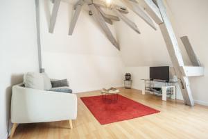 a living room with a white couch and a red rug at Appartement dans le vieux Châteauroux in Châteauroux