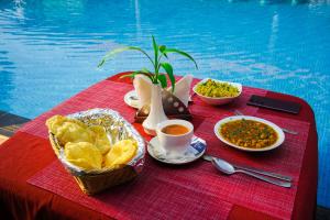 uma mesa com comida e bebidas numa mesa ao lado de uma piscina em Royale Assagao Resort em Assagao