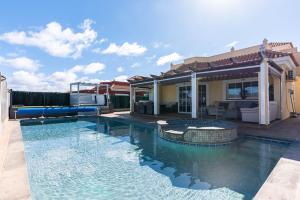a swimming pool in front of a house at Comfortable family house with pool and jacuzzi in Costa de Antigua