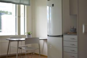 a kitchen with a refrigerator and a table and chairs at Soihtu Stay in Jyväskylä