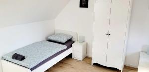 a small white bedroom with a bed and a cabinet at Modern Apartment Bedburg-Hau in Bedburg Hau