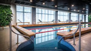 una piscina con bancos y sillas en un edificio en Apartamenti pie jūras Latvijā, en Plieņciems