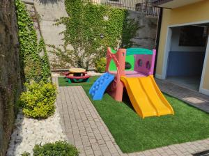 un pequeño parque infantil con un tobogán en el césped en Bardolino Wein Apartments, en Bardolino