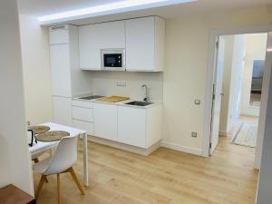 kuchnia z białymi szafkami oraz białym stołem i krzesłem w obiekcie Alameda Lofts Pontevedra w mieście Pontevedra