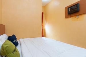 a bedroom with a bed with a tv on the wall at Urbanview Hotel Nisura Homestay Medan by RedDoorz in Sunggal
