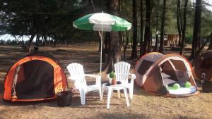 eine Gruppe von Zelten, Stühlen und einem Regenschirm in der Unterkunft Andaman Peace Resort in Ranong