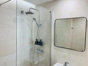 prysznic ze szklanymi drzwiami i lustrem w obiekcie Alameda Lofts Pontevedra w mieście Pontevedra