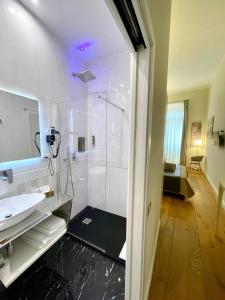 uma casa de banho com uma cabina de duche em vidro e um lavatório. em Antico Corso Charme em Cagliari